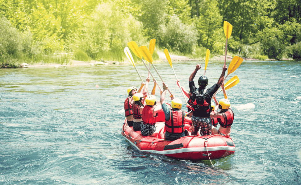 A large raft full of people rafting down a river.